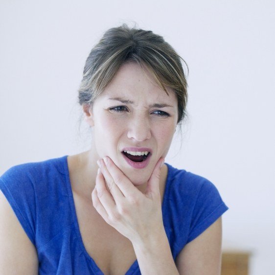 Woman in need of T M J treatment holding jaw in pain