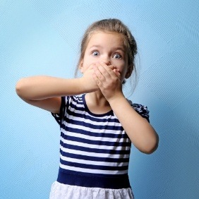 Child with knocked out tooth covering her mouth