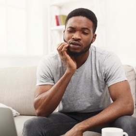 Man with lost filling holding cheek in pain