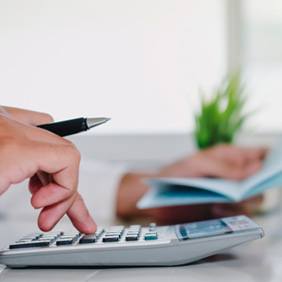 Hand using calculator as person figures cost of dental care